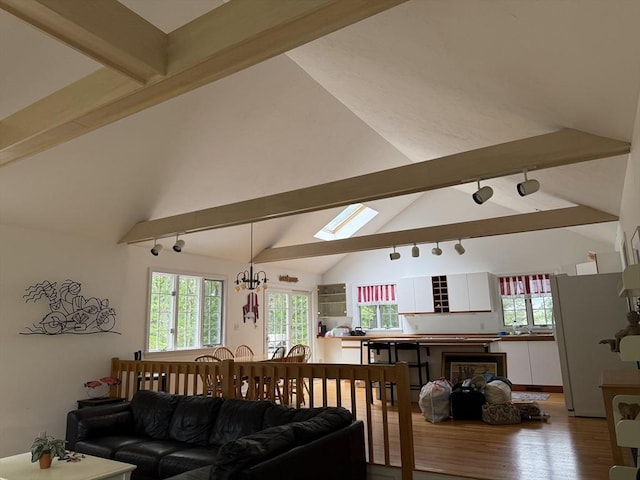 183 Monomoscoy Rd, Mashpee, MA 02649 - living room featuring beamed ceiling, rail lighting, wood finished floors, healthy amount of natural light, and a chandelier