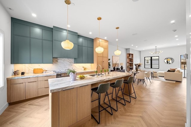 kitchen with a sink, a large island with sink, backsplash, decorative light fixtures, and a kitchen breakfast bar