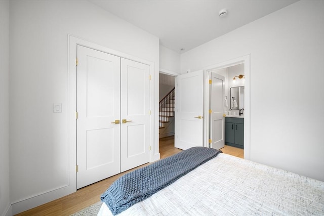 bedroom featuring light wood-style flooring, connected bathroom, and a closet