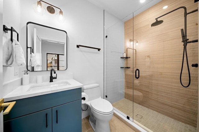 bathroom featuring a shower stall, toilet, and vanity