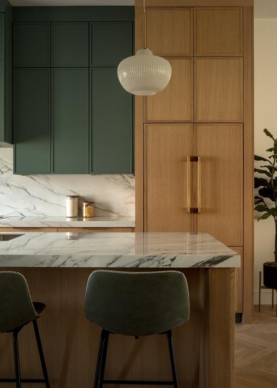 kitchen featuring a breakfast bar, light stone counters, hanging light fixtures, and modern cabinets