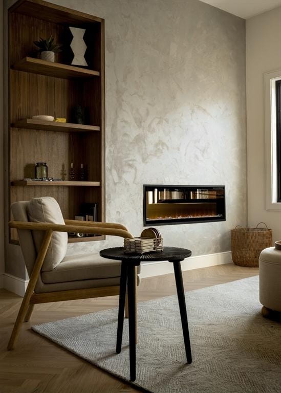 living area with a glass covered fireplace, baseboards, and built in shelves