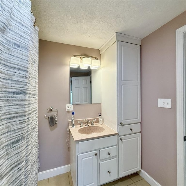 bathroom with tile patterned floors, vanity, baseboards, and a textured ceiling