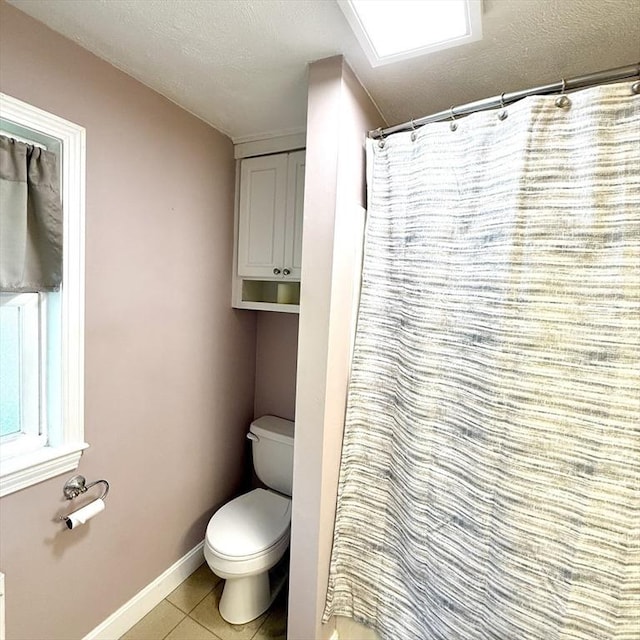 full bath with toilet, tile patterned flooring, baseboards, a shower with curtain, and a textured ceiling