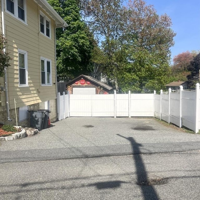 view of side of home with fence, an outbuilding, and driveway