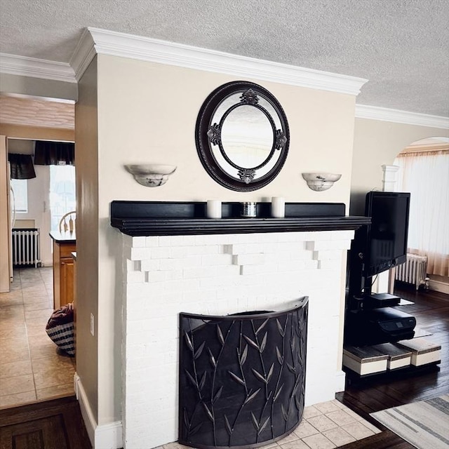 detailed view of radiator heating unit, a textured ceiling, arched walkways, crown molding, and a fireplace