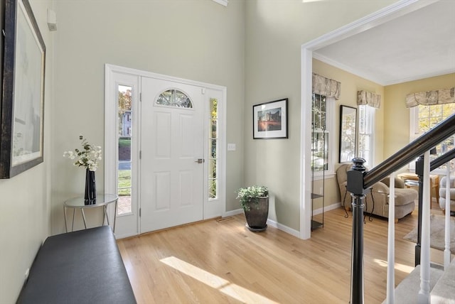 entrance foyer featuring a wealth of natural light, baseboards, light wood finished floors, and stairs