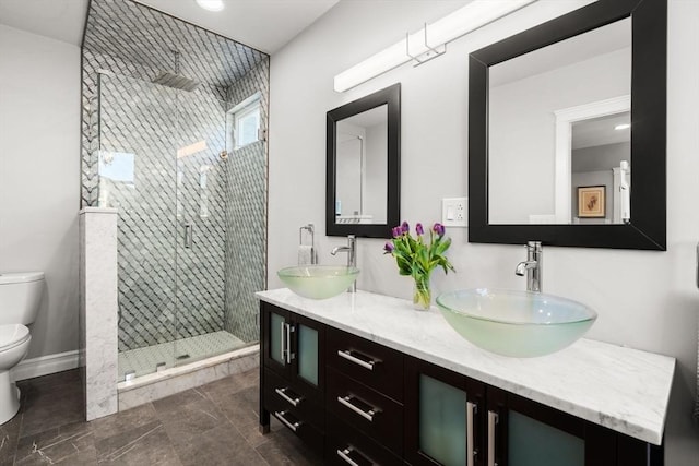 bathroom featuring double vanity, toilet, a shower stall, and a sink