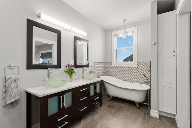 full bath with a sink, tile walls, double vanity, and a freestanding tub