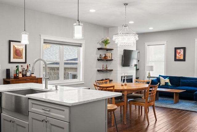 interior space with pendant lighting, light stone countertops, dark wood-style floors, gray cabinets, and a sink