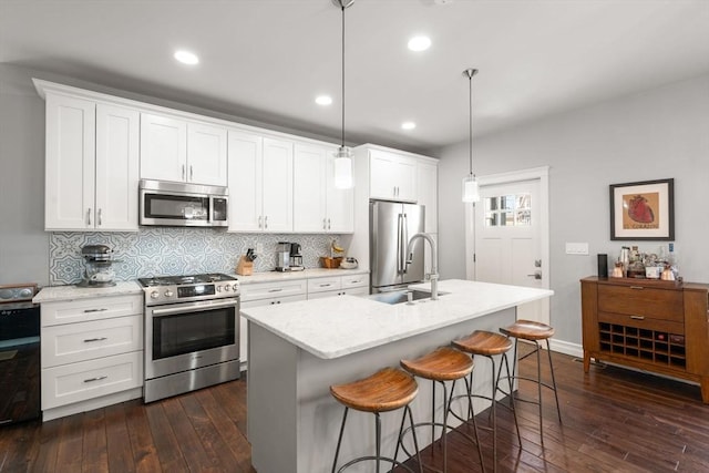 kitchen with decorative backsplash, dark wood-style flooring, appliances with stainless steel finishes, and a kitchen bar