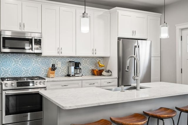 kitchen with a sink, pendant lighting, a breakfast bar area, and stainless steel appliances