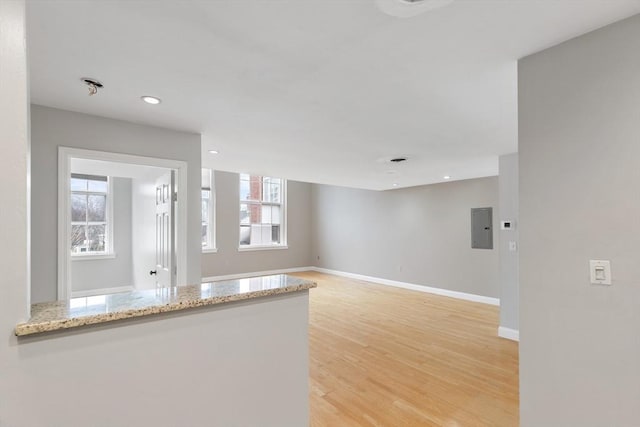 interior space featuring light wood-type flooring, light stone countertops, electric panel, and plenty of natural light