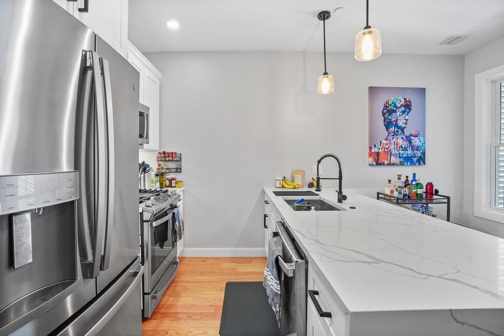 174 W 7th St Unit 1, Boston, MA 02127 - kitchen with appliances with stainless steel finishes, a sink, light wood-style floors, a peninsula, and visible vents