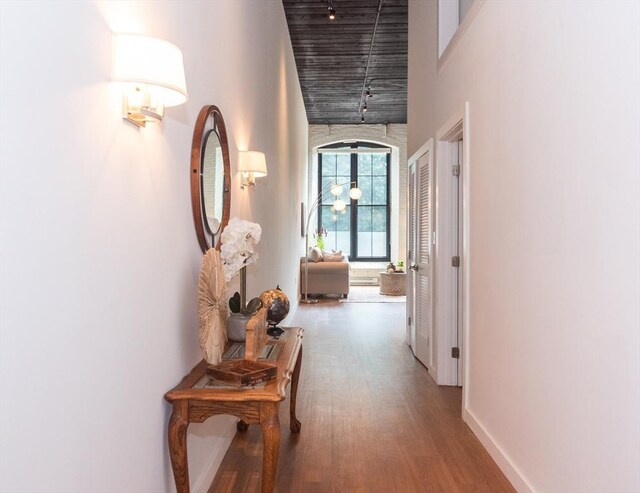 hallway with a towering ceiling and hardwood / wood-style floors