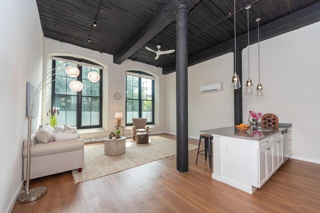 living room featuring a wall unit AC, wood-type flooring, beamed ceiling, and wooden ceiling