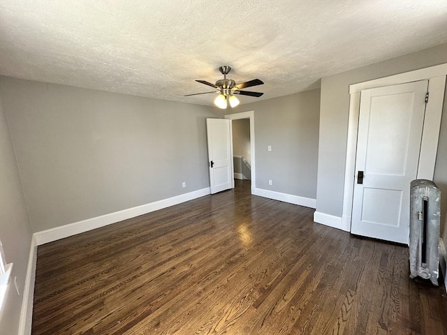 interior space featuring baseboards, a ceiling fan, dark wood-style floors, and a textured ceiling