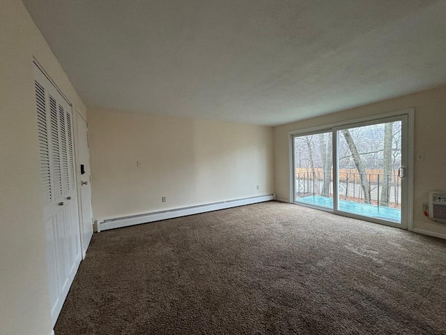 spare room with an AC wall unit, dark colored carpet, and a baseboard heating unit