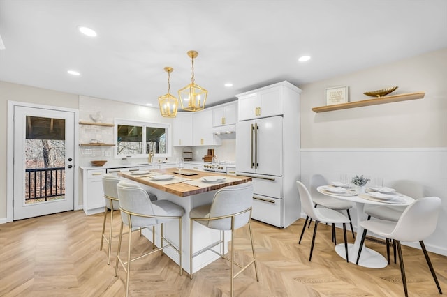 kitchen with white cabinetry, pendant lighting, a healthy amount of sunlight, and high end white fridge