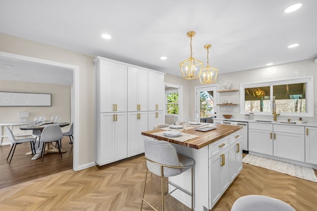 kitchen with white cabinets, decorative light fixtures, a center island, and butcher block counters