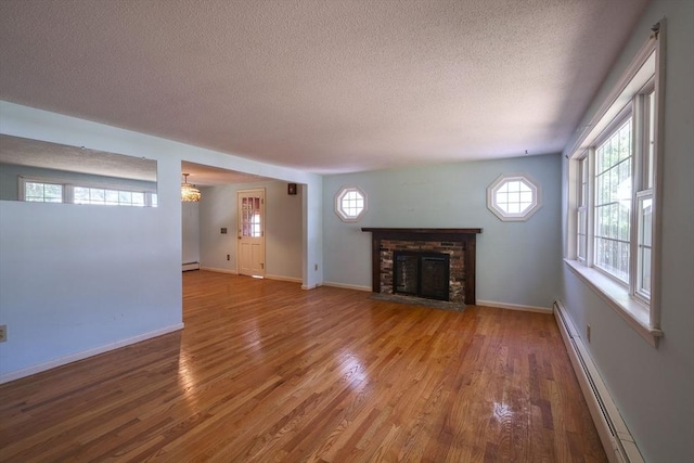 175 Knotty Pine Ln, Barnstable, MA 02632 - unfurnished living room featuring a baseboard radiator, a textured ceiling, wood finished floors, a brick fireplace, and baseboards