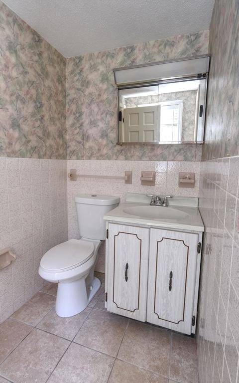 175 Knotty Pine Ln, Barnstable, MA 02632 - half bath with vanity, toilet, a textured ceiling, wallpapered walls, and tile walls