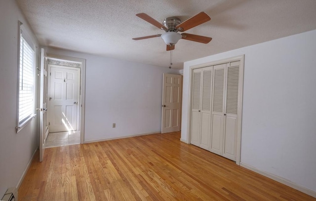175 Knotty Pine Ln, Barnstable, MA 02632 - unfurnished bedroom with a baseboard radiator, light wood finished floors, baseboards, a closet, and a textured ceiling