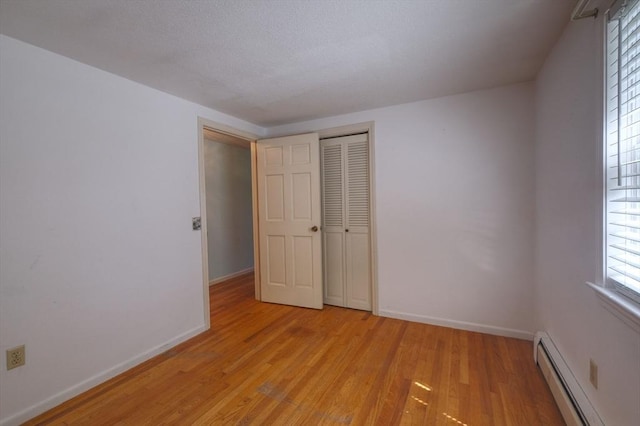 175 Knotty Pine Ln, Barnstable, MA 02632 - unfurnished bedroom with a baseboard radiator, light wood finished floors, baseboards, and a closet