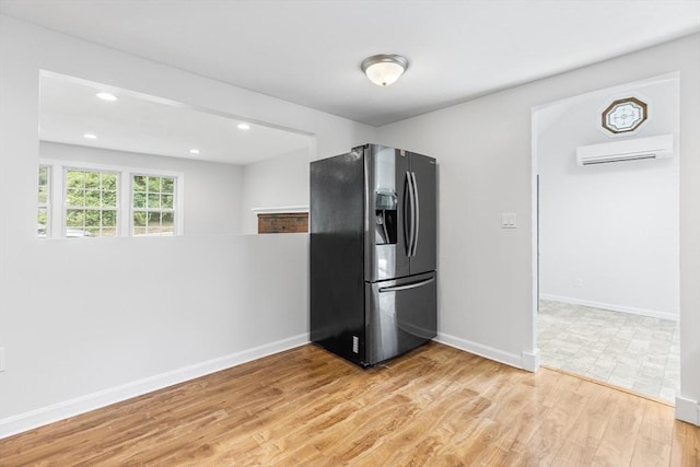 kitchen with light hardwood / wood-style floors, refrigerator with ice dispenser, and a wall mounted air conditioner