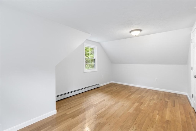 additional living space featuring a baseboard radiator, light wood-type flooring, and lofted ceiling