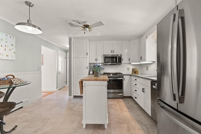 85 Loring Ave, Winchester, MA 01890 - kitchen featuring stainless steel appliances, wooden counters, white cabinets, ornamental molding, and wainscoting