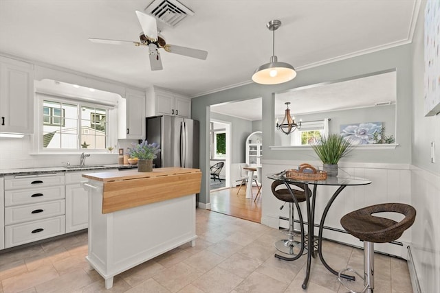 85 Loring Ave, Winchester, MA 01890 - kitchen featuring freestanding refrigerator, butcher block countertops, ornamental molding, white cabinetry, and a wainscoted wall