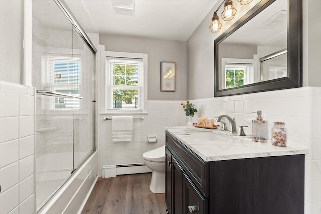 85 Loring Ave, Winchester, MA 01890 - full bathroom featuring a baseboard heating unit, tile walls, wood finished floors, vanity, and shower / bath combination with glass door