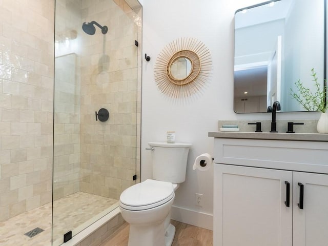 bathroom featuring hardwood / wood-style flooring, vanity, toilet, and tiled shower