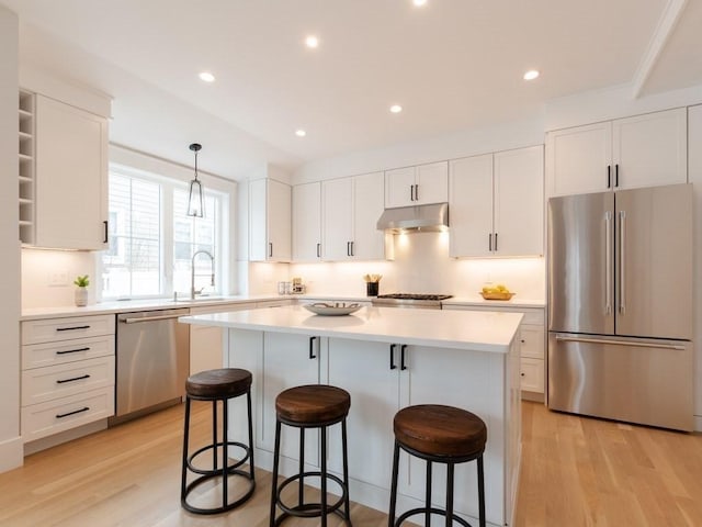 kitchen featuring white cabinetry, a kitchen island, stainless steel appliances, and light wood-type flooring