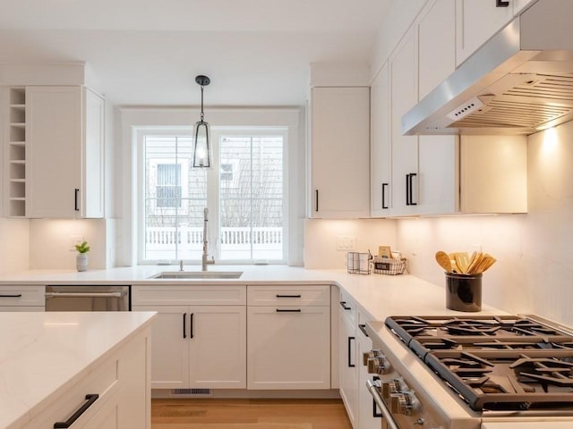 kitchen featuring white cabinets, appliances with stainless steel finishes, light hardwood / wood-style flooring, and pendant lighting