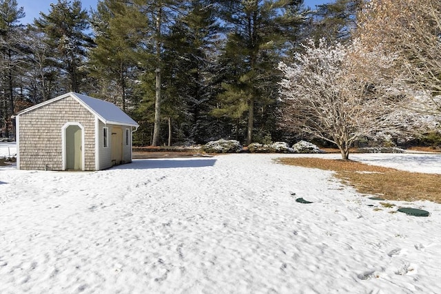 yard layered in snow featuring a shed