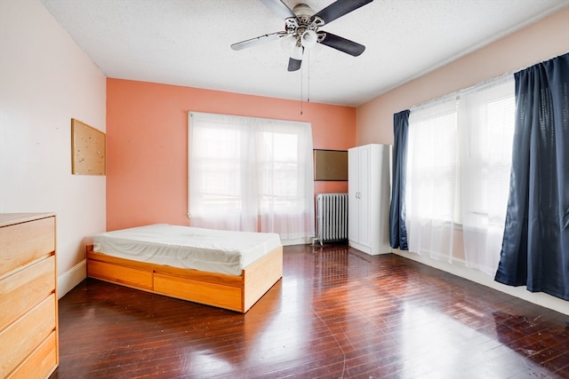 bedroom with radiator, multiple windows, ceiling fan, and dark hardwood / wood-style flooring