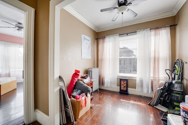 recreation room with wood-type flooring, a textured ceiling, radiator, crown molding, and ceiling fan