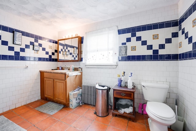 bathroom featuring tile walls, vanity, toilet, and radiator heating unit