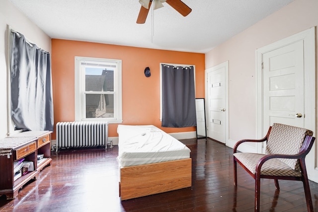 bedroom featuring a textured ceiling, radiator, dark hardwood / wood-style floors, and ceiling fan