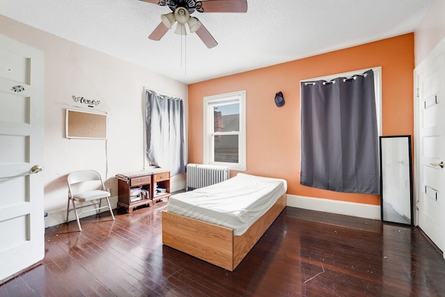 bedroom with a textured ceiling, radiator, hardwood / wood-style floors, and ceiling fan