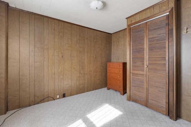 bedroom featuring light colored carpet, a closet, and wood walls