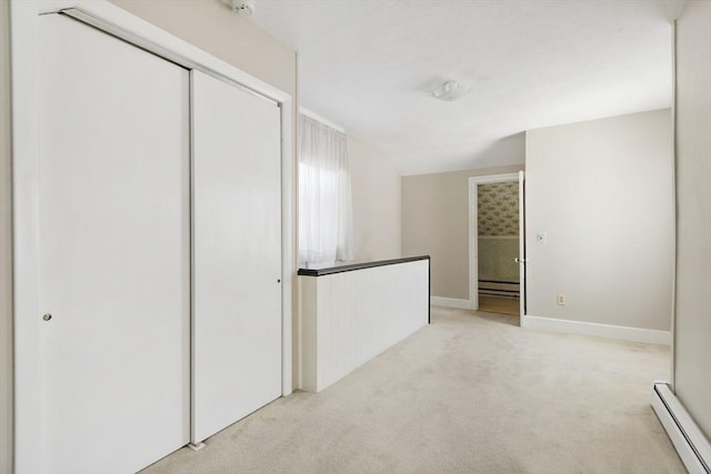 empty room with light colored carpet, baseboards, baseboard heating, and a baseboard radiator