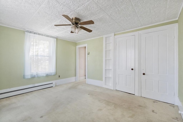 unfurnished bedroom with a ceiling fan, carpet, a baseboard radiator, a closet, and crown molding