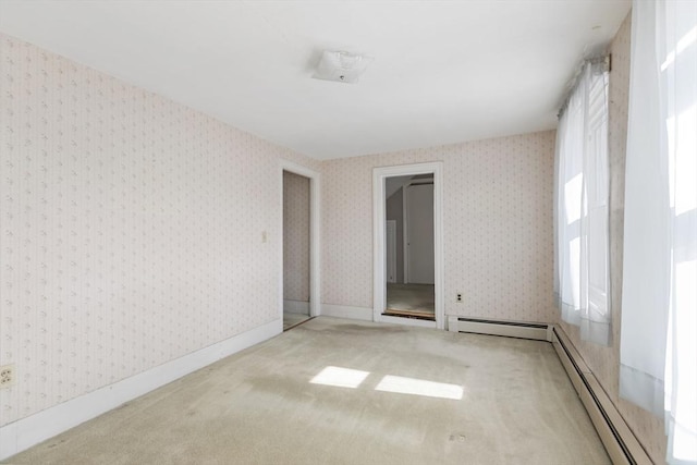 spare room featuring a baseboard heating unit, carpet floors, baseboards, and wallpapered walls