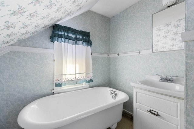 bathroom featuring a freestanding tub, vaulted ceiling, vanity, and wallpapered walls