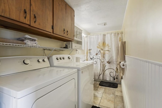 washroom with cabinet space, washing machine and dryer, a wainscoted wall, and a textured ceiling