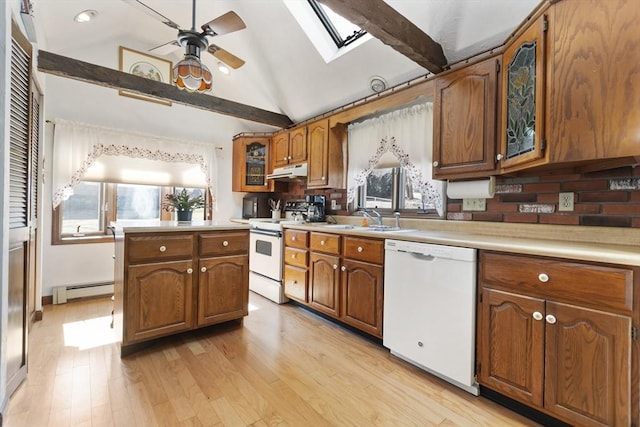 kitchen with a sink, a baseboard radiator, white appliances, and plenty of natural light