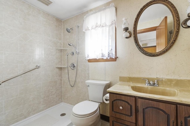 full bath featuring visible vents, toilet, tiled shower, and vanity